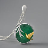 gold bird and planet in green necklace